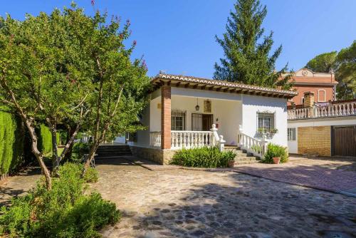 a large white house with a porch and trees at Casa San Rafael, magnífico chalet con gran jardín in Navajas