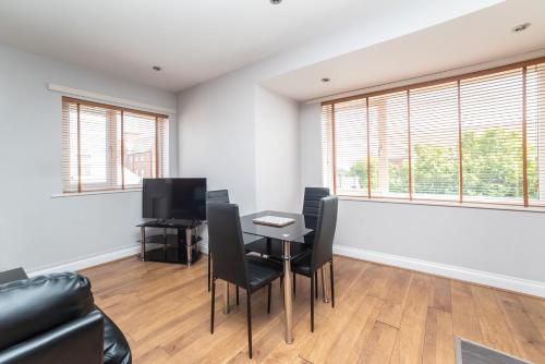 a living room with a table and chairs and windows at The New Mill Apartments in Newcastle upon Tyne