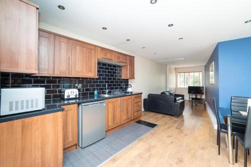 a kitchen with wooden cabinets and a living room at The New Mill Apartments in Newcastle upon Tyne