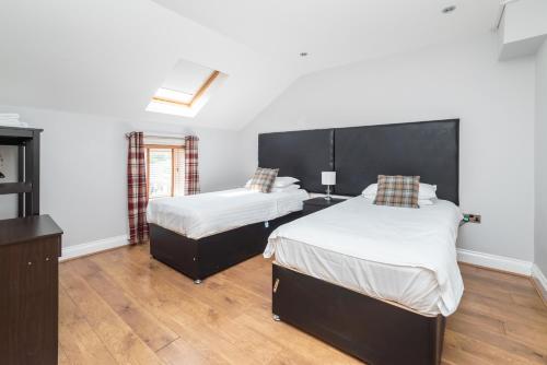 two beds in a room with white walls and wooden floors at The New Mill Apartments in Newcastle upon Tyne