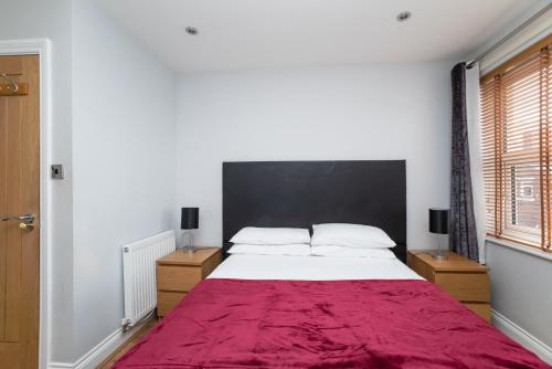 a bedroom with a large bed with a red blanket at The New Mill Apartments in Newcastle upon Tyne
