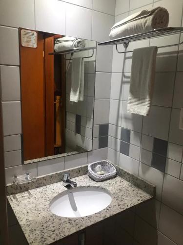 a bathroom with a sink and a mirror and towels at Studio 01 Modelo Flat in Salvador