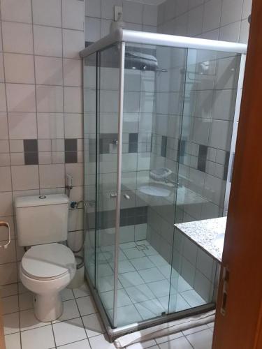 uma casa de banho com um WC e uma cabina de duche em vidro. em Studio 01 Modelo Flat em Salvador