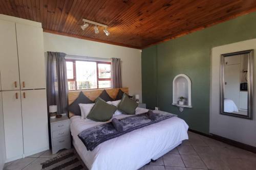 a bedroom with a large white bed with green walls at Cozy, peaceful garden cottage in Cape Town