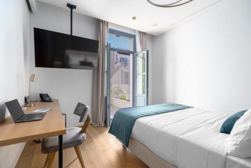 a bedroom with a bed and a desk with a laptop at Hellenic Vibes Smart Hotel in Athens
