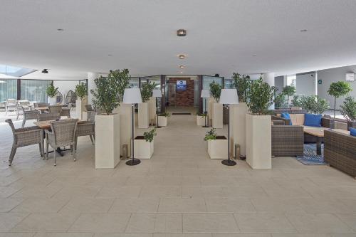 a lobby with tables and chairs and potted plants at Best Western Hotel Trier City in Trier