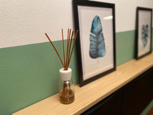 a shelf with pictures and a vase with sticks in it at Pinzolo Wellness Apartment in Pinzolo