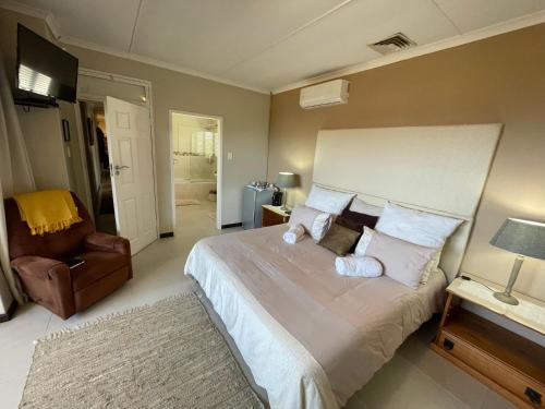 ein Schlafzimmer mit einem großen Bett und einem Stuhl in der Unterkunft Eden Rose Manor B&B in La Mercy
