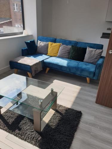 a living room with a blue couch and a glass table at 2 bedroom, 2 bathroom, New Apartment Watford Town Centre in Watford