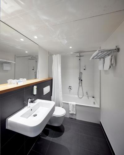 a bathroom with a sink and a toilet and a tub at Best Western Hotel Trier City in Trier