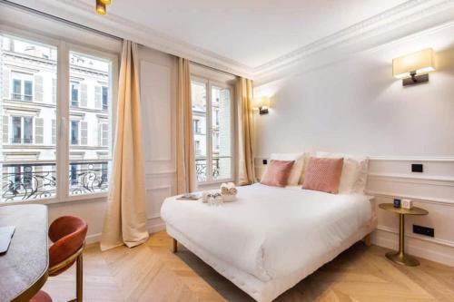 een slaapkamer met een wit bed en een groot raam bij CMG Lafayette - Gare de l'Est in Parijs