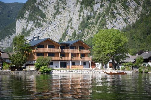 uma casa na costa de um corpo de água em Boutiquehotel Strand Hallstatt - Adults only em Hallstatt