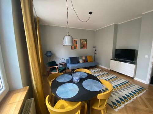 een eetkamer met een tafel en gele stoelen bij Maya's Flats & Resorts 40 - Kolodziejska 7/9E in Gdańsk