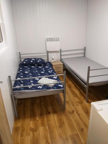 1 dormitorio con 2 camas y suelo de madera en Domek N5 - 2 Pokoje , Kuchnia , Łazienka 5 osobowy - FreezerHause Izdebno- NoclegiGrodziskPL, en Grodzisk Mazowiecki