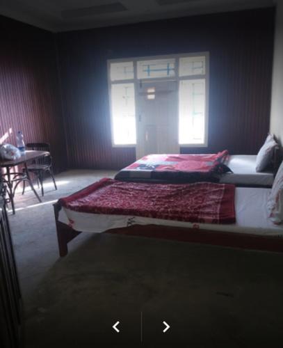 a bedroom with two beds and a table and a window at Happy Heart Hotel & Restaurant in Malam Jabba