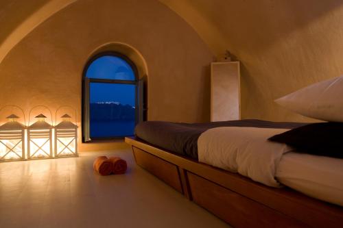 a bedroom with a bed and a large window at Lydia Cavehouse in Oia