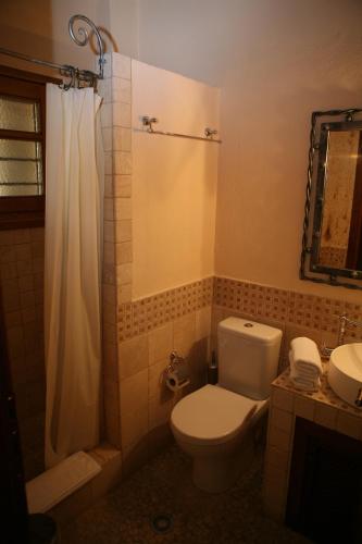 a bathroom with a toilet and a shower and a sink at Roes Suites in Kato Loutraki