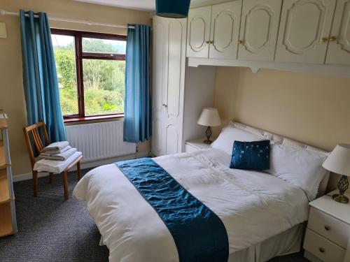 a bedroom with a large bed with blue curtains and a window at Teach Taigh in Kincasslagh