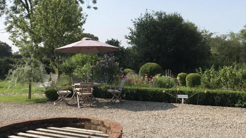 a patio with a table and an umbrella in a garden at Abbey Green Farm in Wem