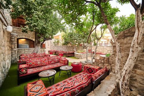 a patio with red couches and tables and trees at Stara Čaršija Hotel & SPA in Bar
