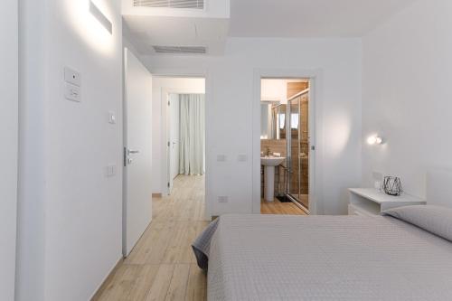 a white bedroom with a bed and a bathroom at Capo Falcone Charming Apartments in Stintino
