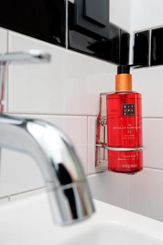a red bottle of lipstick sitting on a bathroom sink at Hotel Brasserie Smits in Wemeldinge