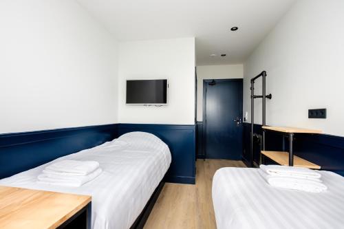 two beds in a room with a tv on the wall at Hotel Brasserie Smits in Wemeldinge