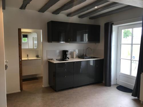 a kitchen with black cabinets and a sink and a window at Les Vallées in Fondettes