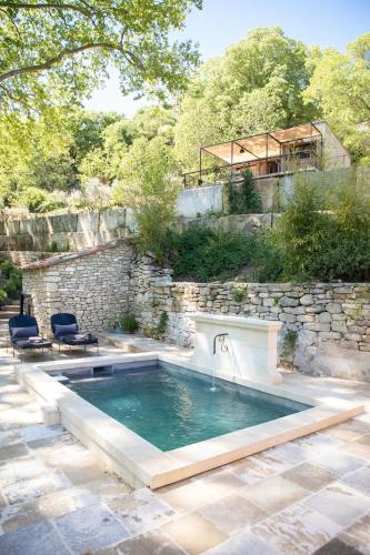une piscine avec une cascade et un mur en pierre dans l'établissement Les Cabanes de la Fontaine, à Lacoste