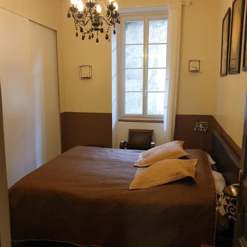 - une chambre avec un lit, un lustre et une fenêtre dans l'établissement Intra Muros Thiers appart 8 pers 3 ch climatisé Wifi tout équipé parking proche, à Avignon