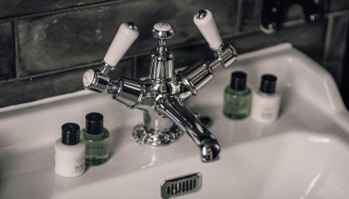 a bathroom sink with a faucet and bottles of soap at The Kirkwall Hotel in Kirkwall