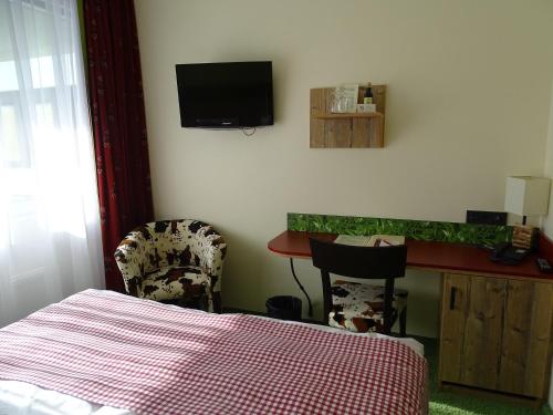a bedroom with a bed and a desk with a tv on the wall at Hotel Da Vinci in Gröbenzell