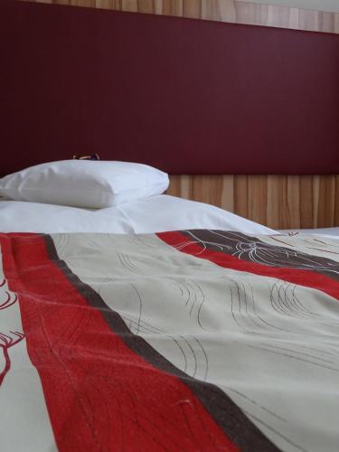 a bed with a red and white blanket on it at Hotel Da Vinci in Gröbenzell