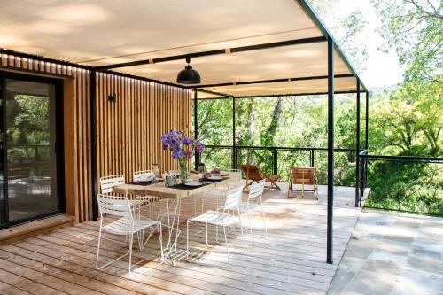 een terras met een tafel en stoelen op een dek bij Les Cabanes de la Fontaine in Lacoste