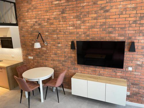 ceglana ściana ze stołem, krzesłami i telewizorem w obiekcie Apartamenty MGA Lividus 15 w Świnoujściu