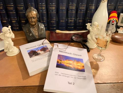 a table with books and a statue and a glass of wine at Ferienwohnung Zur Glewe in Neustadt-Glewe