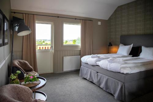 a bedroom with a large bed and two windows at Äppelgården i Båstad in Båstad