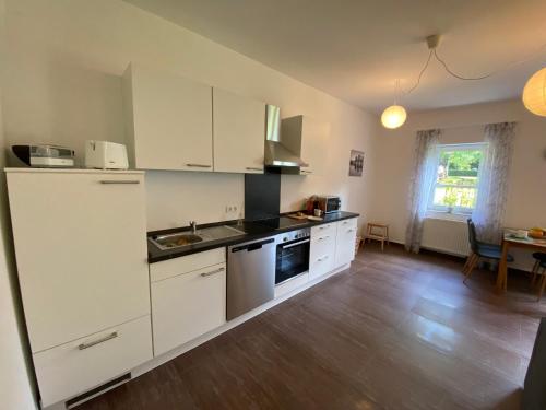 uma cozinha com armários brancos e piso em madeira em Haus Lavendel em Vinningen