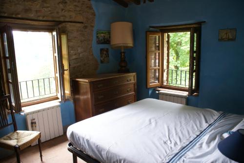 a blue bedroom with a bed and two windows at Tradizione Toscana ristrutturata nel 2021 in Barga