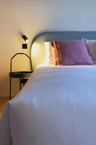 a white bed with a purple pillow and a side table at Oporto CoLiving Monte Ramalde in Porto