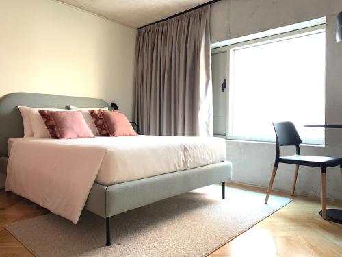 Un dormitorio con una cama con almohadas rosas y una silla en Oporto CoLiving Monte Ramalde, en Oporto