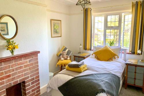 um quarto com uma cama com almofadas amarelas e uma lareira em Hectors House comfortable 4 bed house in mature gardens em Yelverton