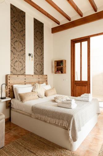 a white bedroom with a large bed with a wooden headboard at Casa Mistela in Jalón