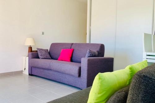 - un canapé violet avec des oreillers colorés dans le salon dans l'établissement Nice Apt Near The Marina Of Porto Vecchio, à Porto-Vecchio