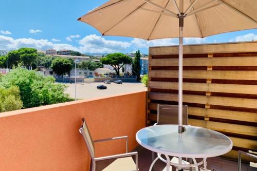 une table et des chaises avec un parasol sur un balcon dans l'établissement Nice Apt Near The Marina Of Porto Vecchio, à Porto-Vecchio