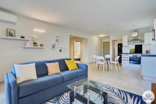 a living room with a blue couch and a kitchen at T3 - Leu Filao, classé 4 étoiles - 70m2 - Plage et Lagon de Saint-Leu in Saint-Leu
