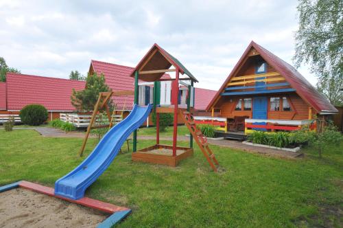 a playground with a slide in front of a house at Ośrodek Wczasowy Domino Bis in Dźwirzyno