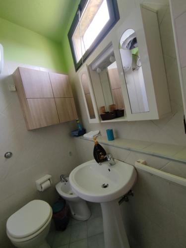 een badkamer met een wastafel, een toilet en een spiegel bij SANTANTONIO in Tortolì
