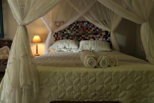 a bedroom with a canopy bed with towels on it at Sítio Pássaro Ímpar - Para pousar e repousar in Curuçá