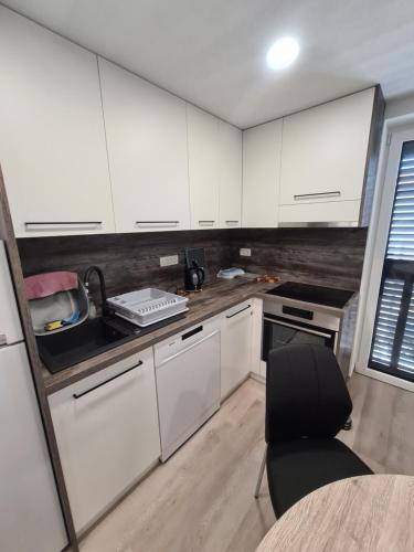 a kitchen with white cabinets and a table and a chair at Portorož Apartments in Portorož
